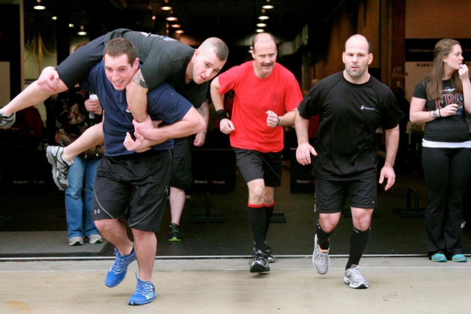 first responder athletes doing buddy carry on a run